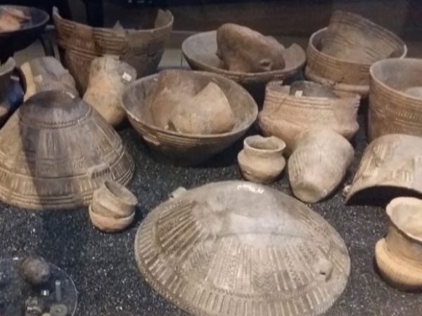 Een vitrine vol met aardewerken potten en schalen