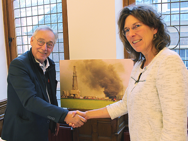 Jacob Melissen en Corinne Rodenburg van het Drents Archief geven elkaar een hand met op de achtergrond een van de foto's uit de fotocollectie van Persburo Melissen