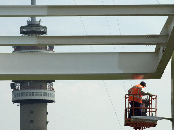 man met oranje hesje op hoogwerker pleegt onderhoud aan brug in Hoogersmilde, nabij Televisietoren